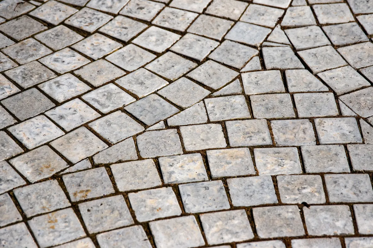 Cobblestone setts laid in overlapping fan arcs on an older path
