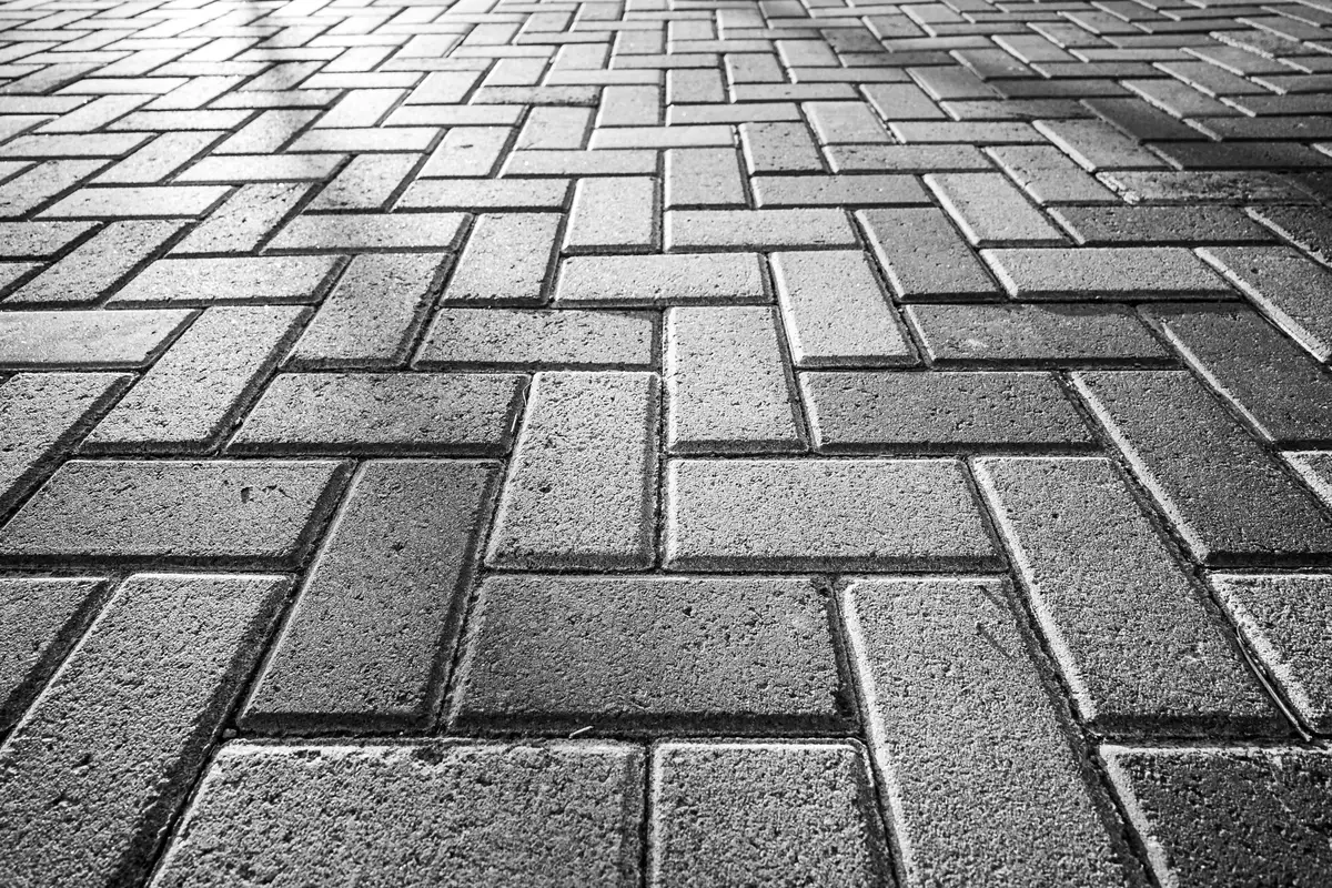 Grey herringbone paving with low light raking across the joints