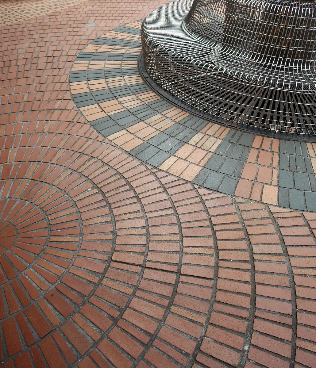 Clay pavers laid in fan arcs around a tree grate in a public square