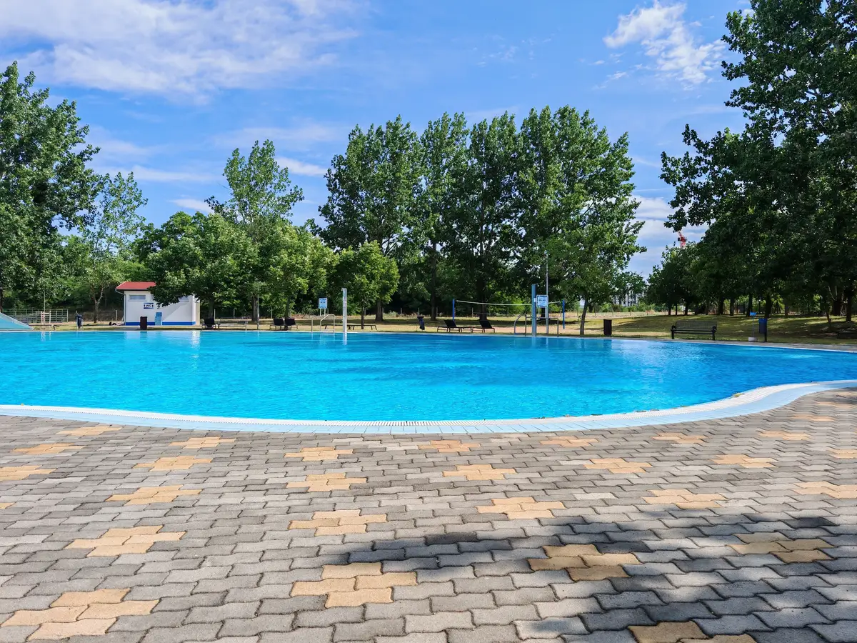 An interlock pool deck running back from the water's edge on landscaped grounds