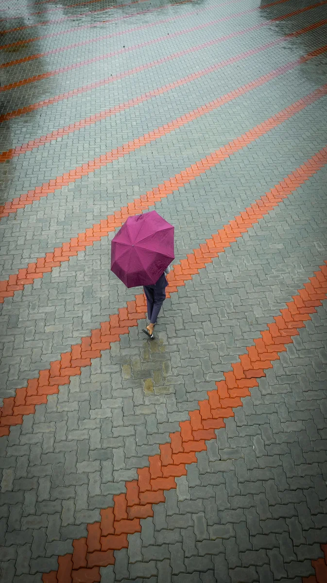 Rain falling across a large interlock plaza banded in grey and orange